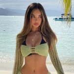 Close-up of Dani Torres wearing a black bikini and green crochet top by the ocean