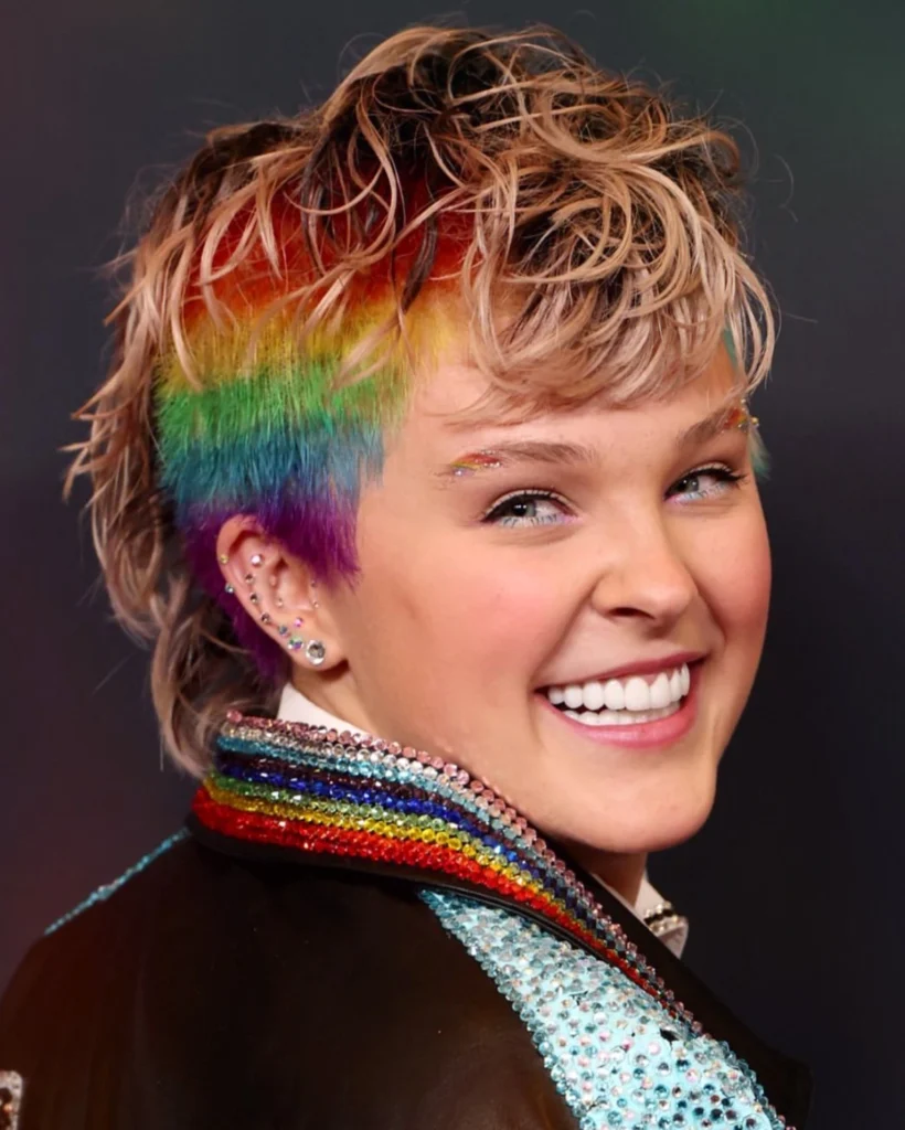 Close-up of JoJo Siwa with rainbow-dyed hair and a rhinestone-collared jacket