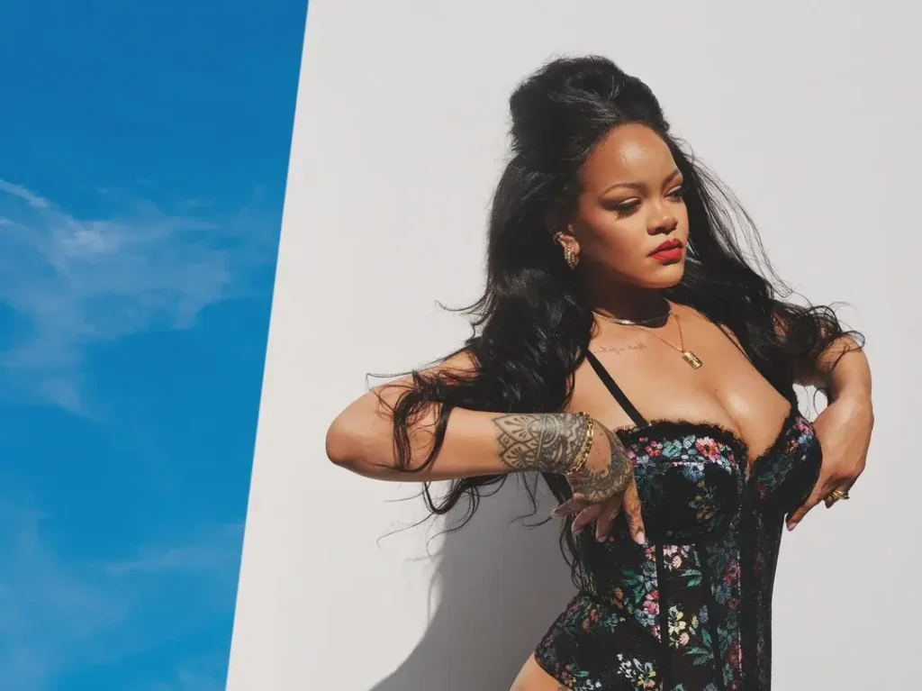 Close-up of Rihanna in a floral Savage X Fenty corset, styling her hair with gold jewelry visible